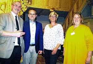 Vier Menschen schauen in die Kamera und lächeln