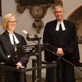 Zwei Menschen in geistlicher Kleidung stehen nebeneinander, die Frau spricht in ein Mikrofon