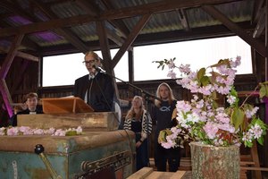 Eine Frau steht hinter einem Altar, im Vordergrund sind Blumen zu sehen
