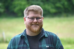 Ein Mann steht draußen im Grünen. 