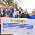 Eine Gruppe Menschen steht hinter einem Banner