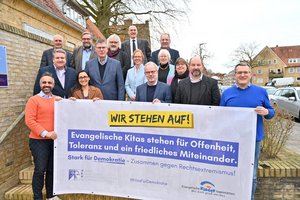 Eine Gruppe Menschen steht hinter einem Banner