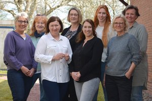 Acht Frauen stehen draußen zusammen als Gruppe.