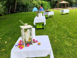 Weiß gedeckte Tische mit Taufkerzen im Freien