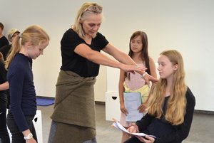 Eine Frau erklärt drei Kindern das Theaterspielen.