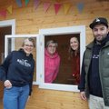 Vier Menschen und ein Spielhaus, zwei schauen zum Fenster hinaus, zwei stehen davor