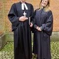 Ein Mann und eine Frau in geistlicher Kleidung lächeln in die Kamera