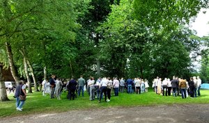 Viele festlich gekleidete Menschen unter Bäumen