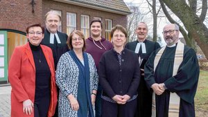 Sieben Menschen stehen vor einem Gebäude