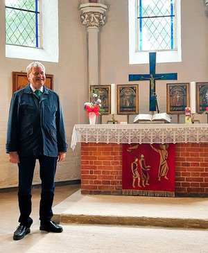 Ein älterer Herr steht neben einem Altar