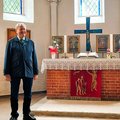 Ein älterer Herr steht neben einem Altar
