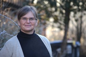 Eine Frau mit kurzen gescheitelten Haaren und einer Brille