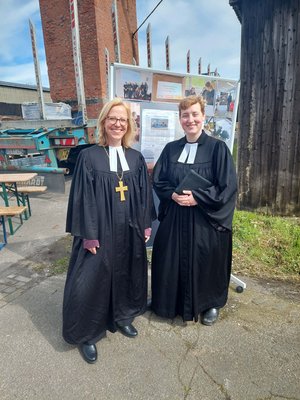 Zwei Frauen in schwarzem Talar stehen vor einem Gebäude