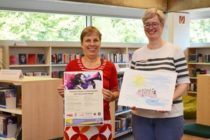 Zwei Frauen stehen vor Bücherregalen. 