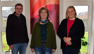 Ein Mann und zwei Frauen lächeln in die Kamera