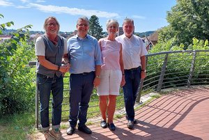 Vier Menschen stehen im Sonnenschein an einen Zaun gelehnt