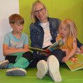 Eine Frau liest zwei Kindern ein Buch vor