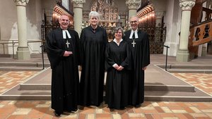 Zwei Männer und zwei Frauen, alle in schwarz, in einer Kirche