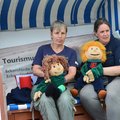 Zwei Frauen sitzen mit zwei Handpuppen in einem Strandkorb