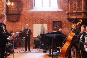 Mehrere Menschen mit Musikinstrumenten in einem Kirchraum