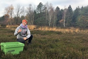 Junger Mensch neben grüner Kiste auf Wiese